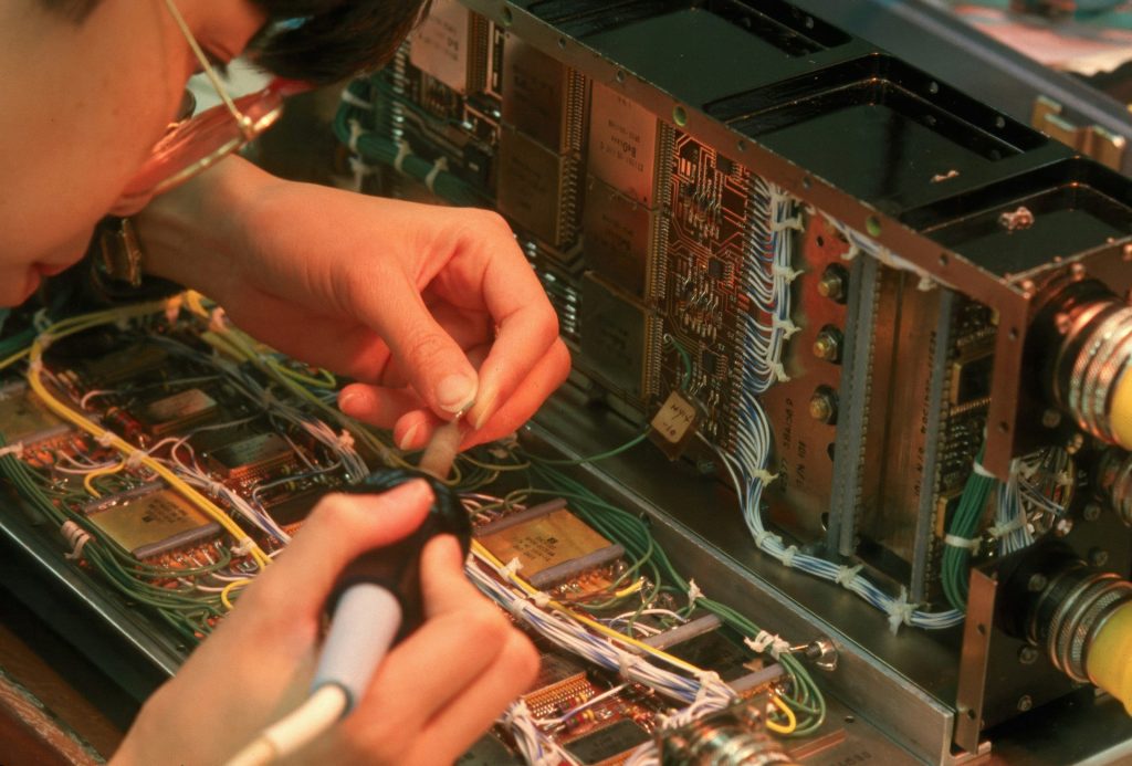 Person working on complex electronic circuitry with wires